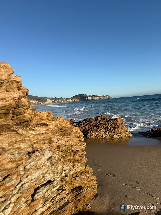 Ground-level photo of rocks on the beach looking toward a headland